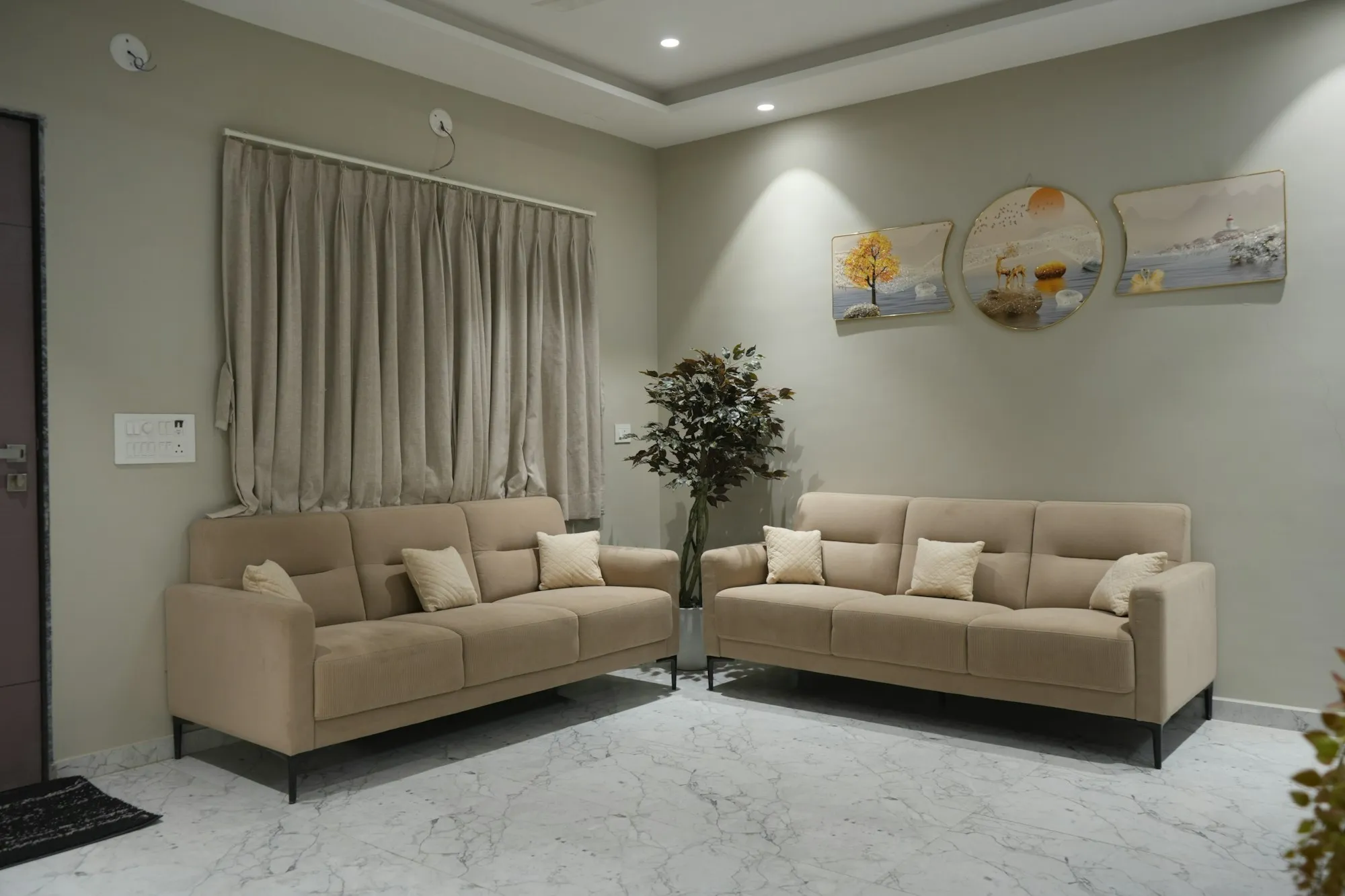 Ilustrasi suasana ruang tamu dengan dua sofa kain berwarna beige.